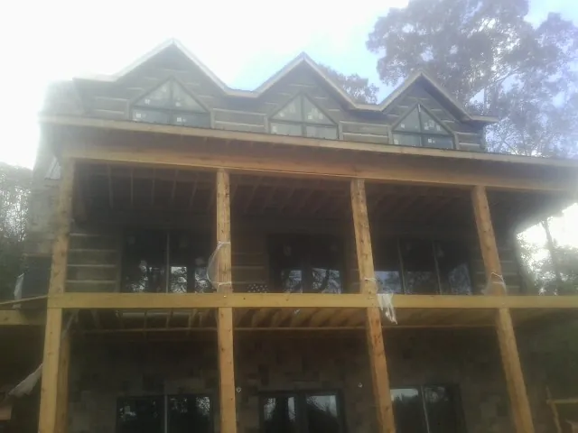 Dormers and porch framing on a large log home under construction — Roof Coating work by our crew in Reynolds