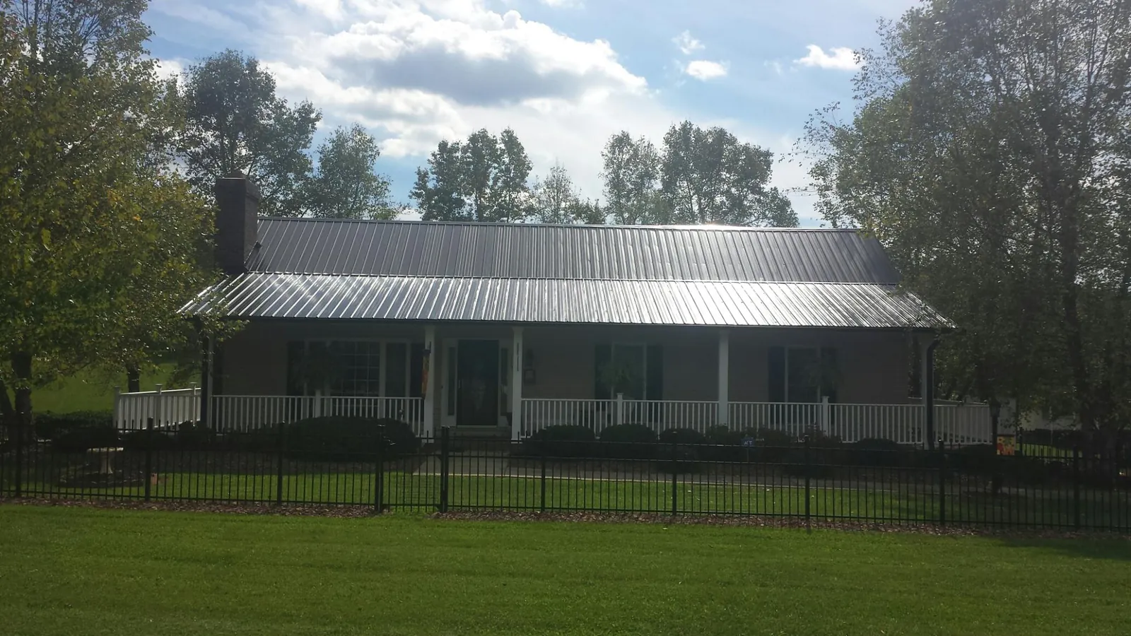 Gray metal roof on a brick ranch with a full width front porch — Gutter Guard Installation work by our crew in Reynolds